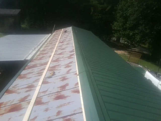 Old rusted panels beside newly installed green metal roofing — Wind Damage Roof Repair by Roofing Brothers in Winfield