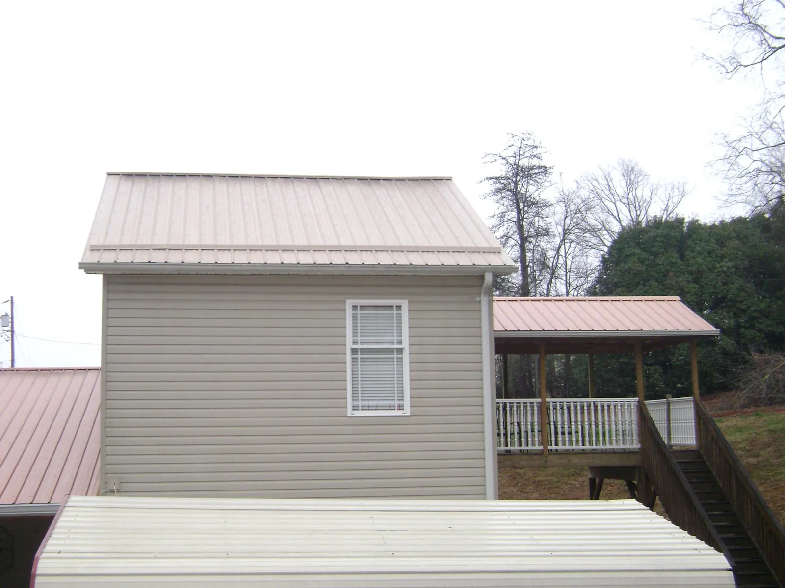 Tan metal roofs on a two story addition and attached porch, from a Roof Replacement job in Winfield